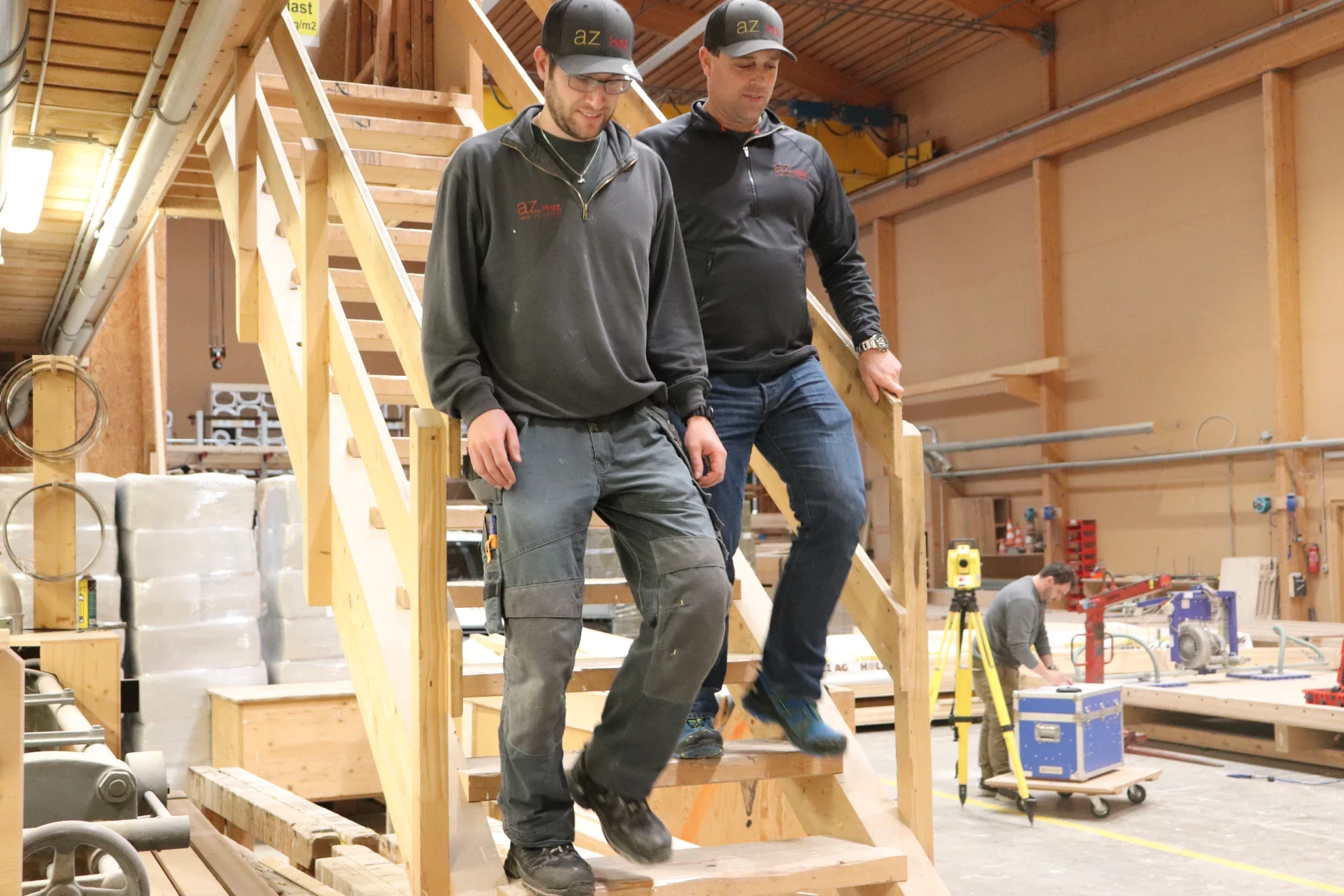Zwei Personen steigen eine Holztreppe hinunter